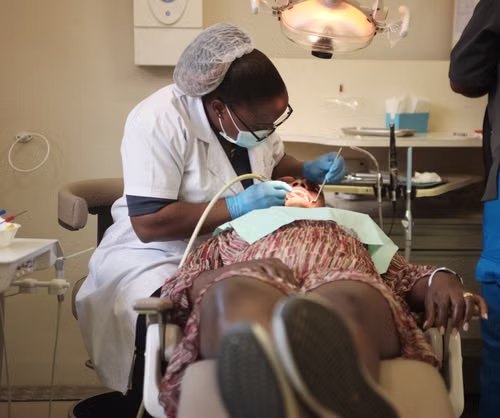 A dentist in a mask and gloves treating a patient in a dental chair