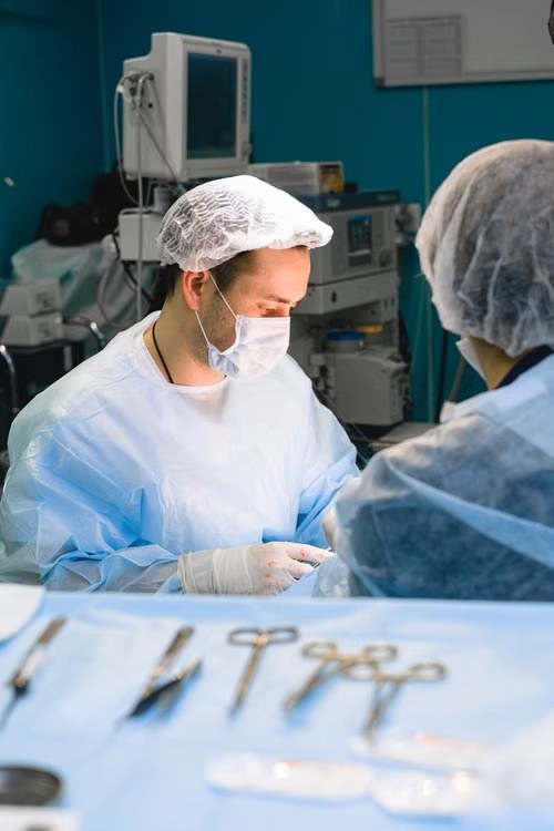 A clinician in a mask, gown and gloves at work, with instruments laid out in front